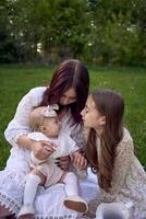 sisters of different ages hug each other tenderly on a picnic in the garden photo