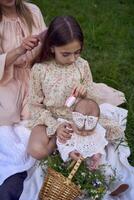 the mother combs the older daughter's hair, and the older daughter combs the younger daughter's hair photo