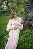 hermosa madre es amamantamiento su bebé niña en el jardín foto