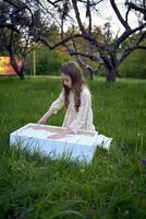 a cute girl in a pastel dress draws with sand on a special table photo