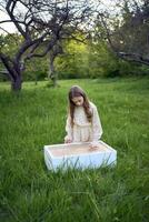 a cute girl in a pastel dress draws with sand on a special table photo