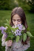 un retrato de un hermosa joven mujer con un ramo de flores de lilas foto