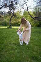 a baby girl walks holding her mother's hands in the park photo