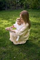 a mother puts shoes on her baby girl in the park photo