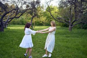 un madre y su Adolescente hija son abrazando y jugando en el jardín foto