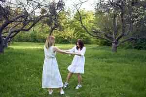 a mother and her teenage daughter are hugging and playing in the garden photo