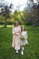 a mother and daughter in pastel dresses walk through the garden with a basket of flowers photo