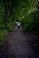 el pequeño niña es corriendo alrededor el parque foto