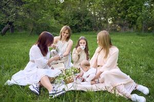 two women and their children having a picnic on the lawn photo