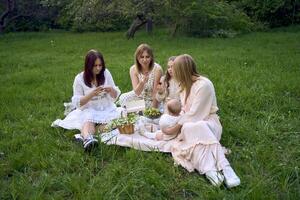 two women and their children having a picnic on the lawn photo