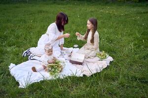 sisters of different ages hug each other tenderly on a picnic in the garden photo