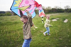 two little sisters and mother run and launch a kite in a field photo