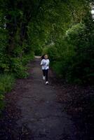 el pequeño niña es corriendo alrededor el parque foto