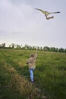 8 años niña moscas un cometa en un campo en un tormenta foto