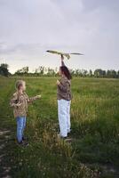 two little sisters and mother run and launch a kite in a field photo
