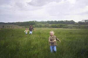 two little sisters and mother run and launch a kite in a field photo