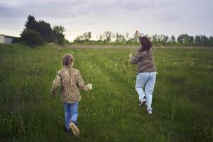 two little sisters and mother run and launch a kite in a field photo