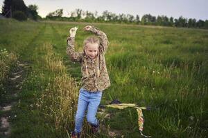 8 años niña moscas un cometa en un campo en un tormenta foto