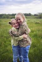 sisters hug and protect each other from the wind in the field photo