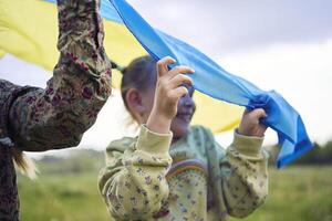 two little girls in the field under the Ukrainian flag in rain photo