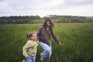 two little sisters and mother run and launch a kite in a field photo