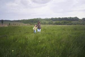 two little sisters and mother run and launch a kite in a field photo