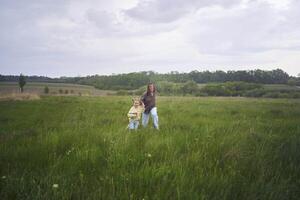 two little sisters and mother run and launch a kite in a field photo