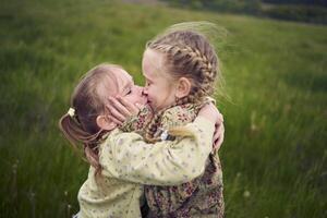 two sisters hug and kiss in the field photo