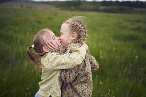 two sisters hug and kiss in the field photo