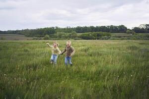 beautiful blonde sisters play with a dandelion in the field photo