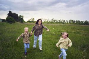 mother and children run holding hands in the field photo