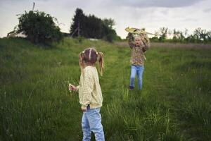 two little sisters repair and fly a kite in a field photo