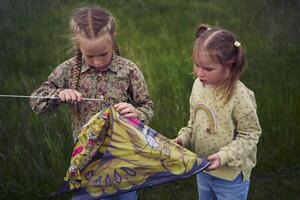 two little sisters repair and fly a kite in a field photo