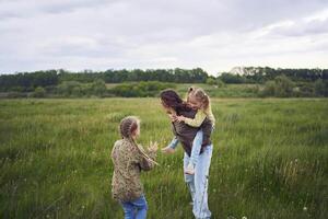 un madre rollos su hijas en su atrás, jugando caballo, Besos y abrazos foto