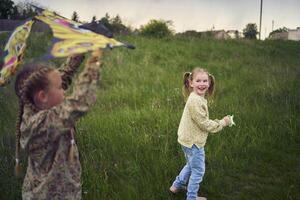 two little sisters repair and fly a kite in a field photo