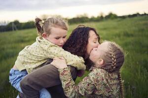 a mother rolls her daughters on her back, playing horse, kisses and hugs photo