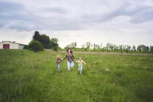 mother and children run holding hands in the field photo