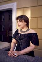 a medium-sized woman in a black corset near a theater with antique columns photo