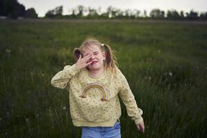 un hermosa rubio niña con su juguete conejito es jugando en el campo foto