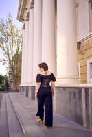 a medium-sized woman in a black corset near a theater with antique columns photo