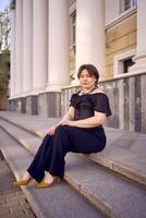 a medium-sized woman in a black corset near a theater with antique columns photo