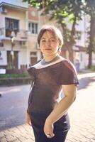 a medium size woman in a black corset and wide leg trousers walks through the city in the morning light photo