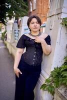 a medium size woman in a black corset and wide leg trousers walks through the city in the morning light photo