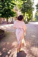 plus size woman in peach fuzz dress dancing on the streets of the morning city photo