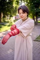 plus size woman in peach fuzz dress and red translucent gloves dancing in the morning city streets photo