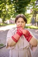 plus size woman in peach fuzz dress and red translucent gloves dancing in the morning city streets photo