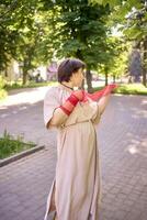 plus size woman in peach fuzz dress and red translucent gloves dancing in the morning city streets photo