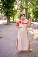 plus size woman in peach fuzz dress and red translucent gloves dancing in the morning city streets photo