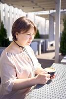 a medium sized woman in peach fuzz dress with cup of coffee in coffee shop in morning light photo