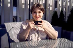 a medium sized woman in peach fuzz dress with cup of coffee in coffee shop in morning light photo